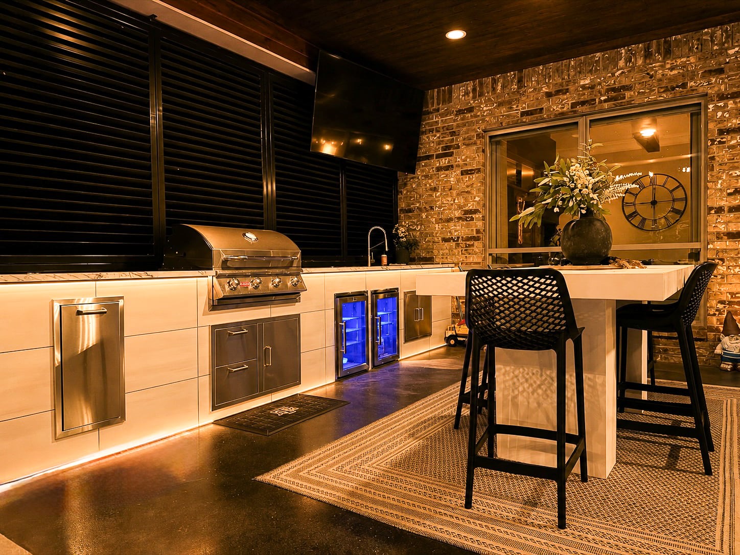 Illuminated outdoor kitchen with grill, refrigeration and bar